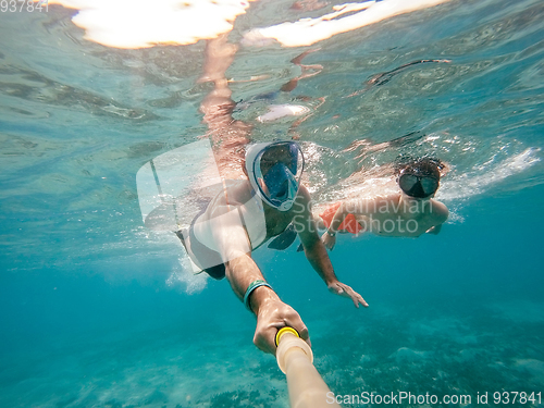 Image of father and son snorkel in shallow water on coral fish