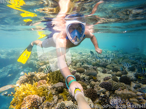 Image of man snorkel in shallow water on coral fish