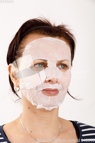 Image of housewife woman with a sheet mask on her face