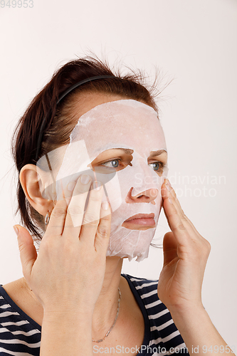 Image of housewife woman with a sheet mask on her face