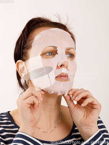 Image of housewife woman with a sheet mask on her face