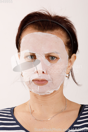 Image of housewife woman with a sheet mask on her face