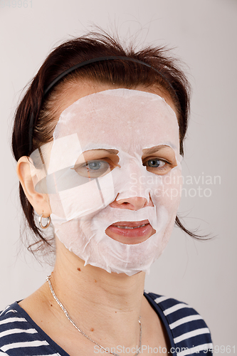 Image of housewife woman with a sheet mask on her face