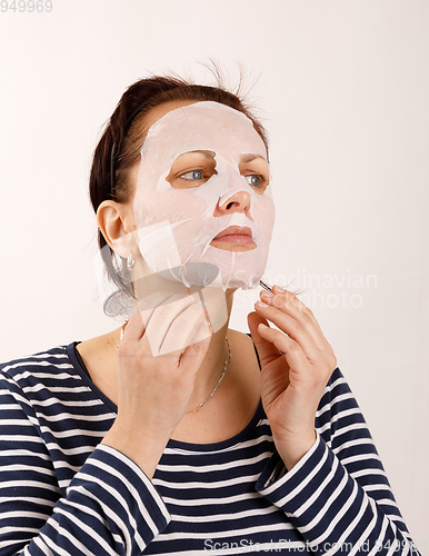 Image of housewife woman with a sheet mask on her face