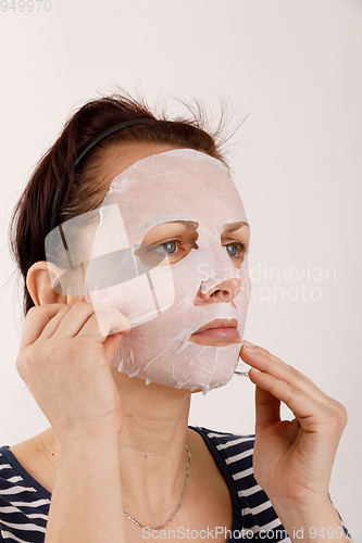 Image of housewife woman with a sheet mask on her face