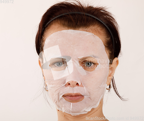 Image of housewife woman with a sheet mask on her face