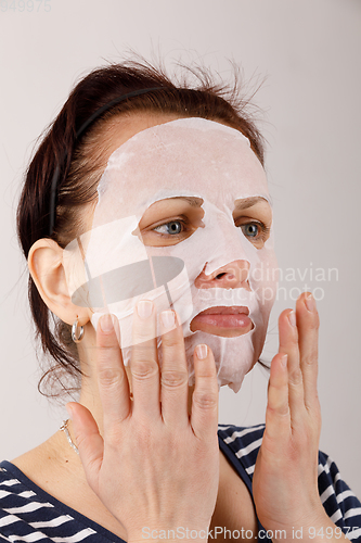 Image of housewife woman with a sheet mask on her face