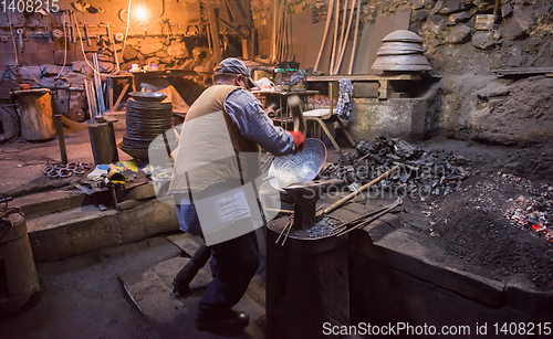 Image of traditional blacksmith manually forging the molten metal