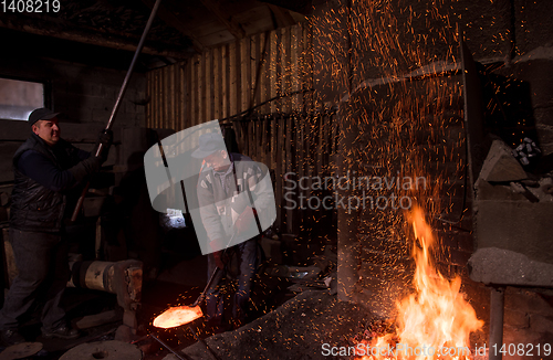 Image of blacksmith workers using mechanical hammer at workshop