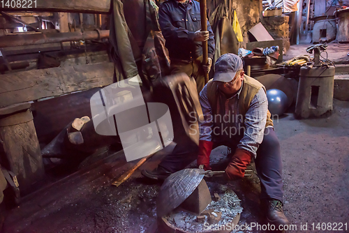 Image of blacksmith workers using mechanical hammer at workshop