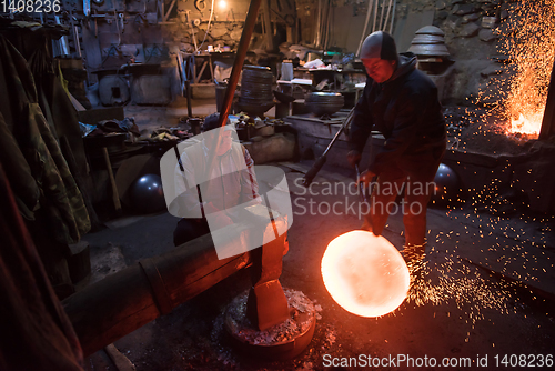 Image of blacksmith workers using mechanical hammer at workshop