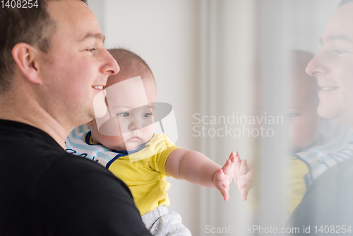 Image of young father holding baby near the window at home