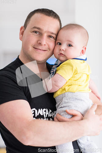 Image of young father holding baby near the window at home