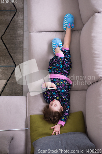 Image of top view of little girl using a smartphone on the sofa