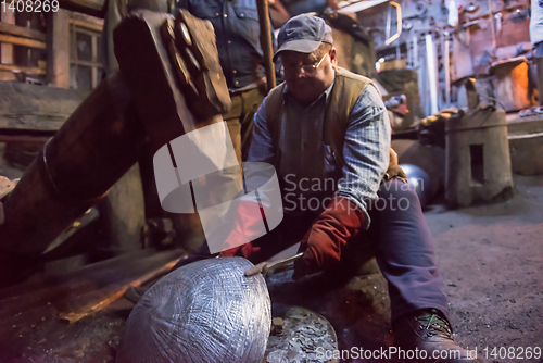 Image of blacksmith workers using mechanical hammer at workshop