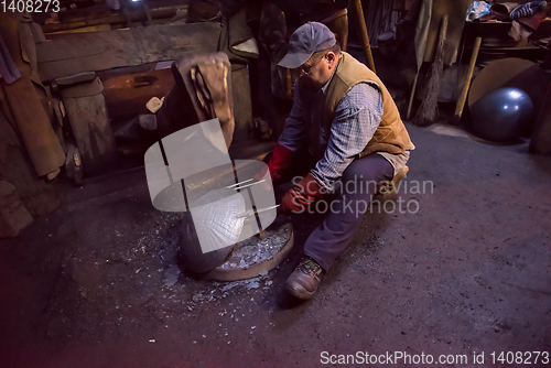 Image of blacksmith workers using mechanical hammer at workshop