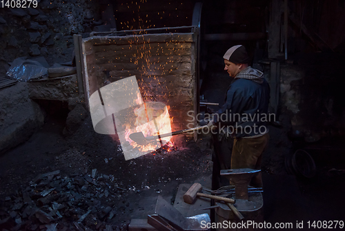 Image of young traditional Blacksmith working with open fire