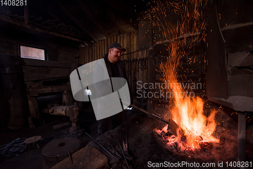 Image of young traditional Blacksmith working with open fire