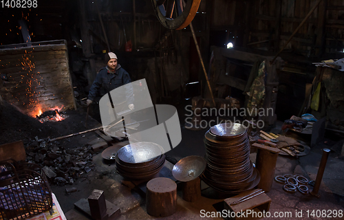 Image of young traditional Blacksmith working with open fire