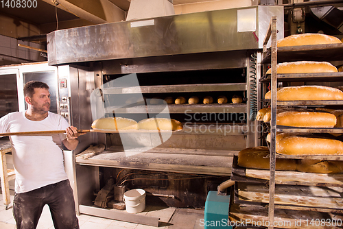 Image of bakery worker taking out freshly baked breads