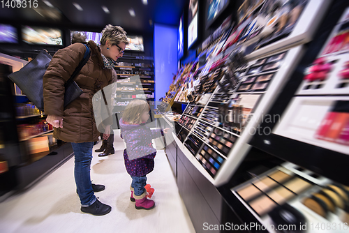 Image of young mother and her little daughter buying makeup