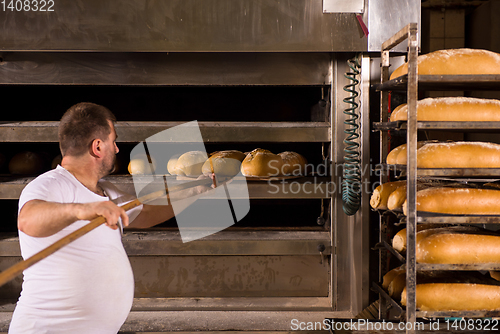 Image of bakery worker taking out freshly baked breads