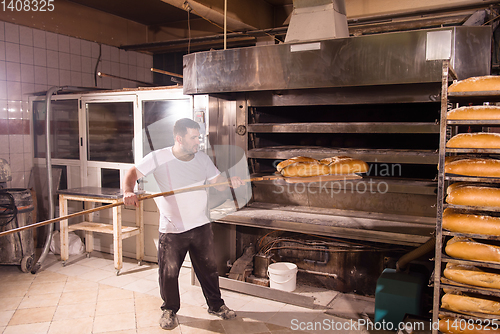 Image of bakery worker taking out freshly baked breads