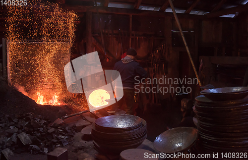 Image of blacksmith workers using mechanical hammer at workshop