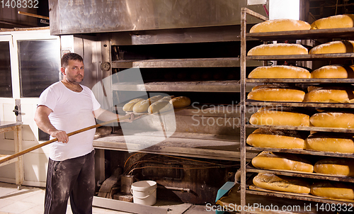 Image of bakery worker taking out freshly baked breads