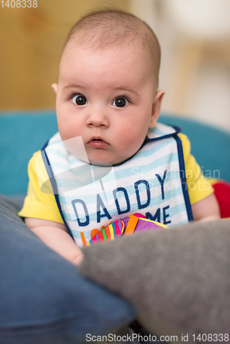 Image of baby boy sitting between the pillows on sofa