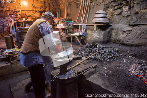 Image of traditional blacksmith manually forging the molten metal