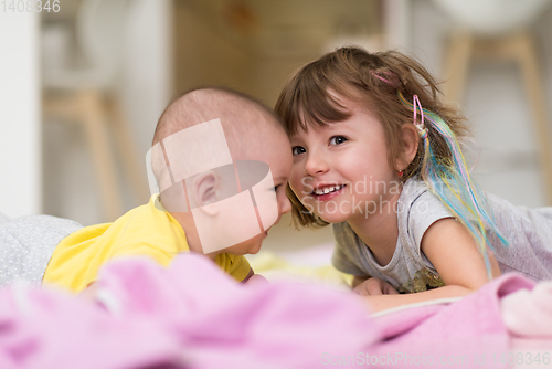 Image of little sister and her baby brother playing at home