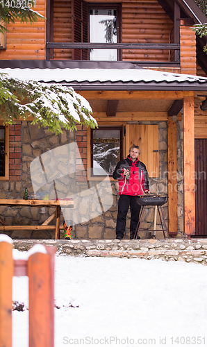 Image of young man cooking meat on barbecue