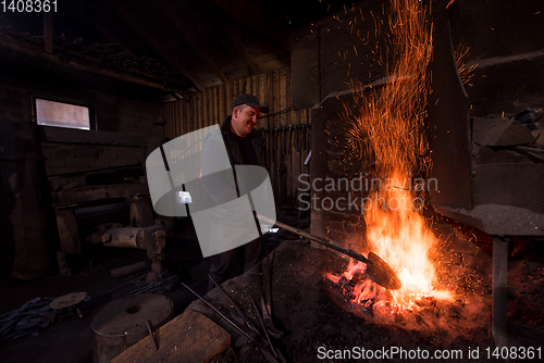 Image of young traditional Blacksmith working with open fire