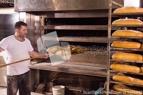 Image of bakery worker taking out freshly baked breads