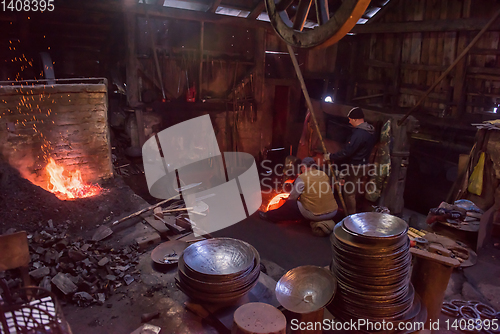 Image of blacksmith workers using mechanical hammer at workshop