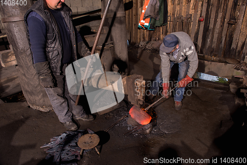 Image of blacksmith workers using mechanical hammer at workshop