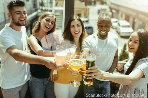 Image of Young group of friends drinking beer and celebrating together
