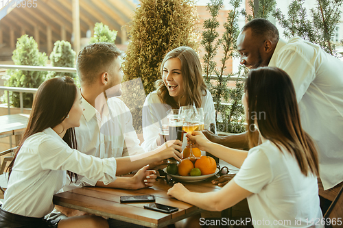 Image of Young group of friends drinking beer and celebrating together