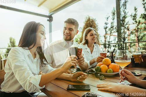 Image of Young group of friends drinking beer and celebrating together