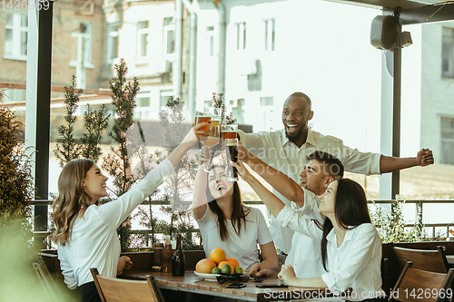 Image of Young group of friends drinking beer and celebrating together