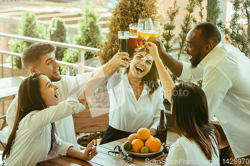 Image of Young group of friends drinking beer and celebrating together