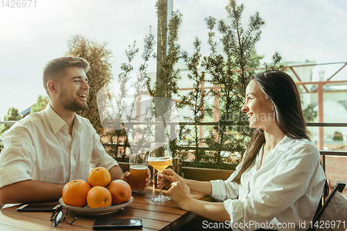 Image of Young friends or couple drinking beer and celebrating together