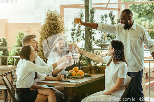 Image of Young group of friends drinking beer and celebrating together