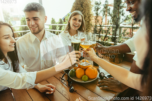 Image of Young group of friends drinking beer and celebrating together