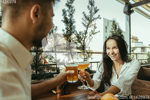 Image of Young friends or couple drinking beer and celebrating together