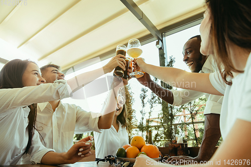 Image of Young group of friends drinking beer and celebrating together