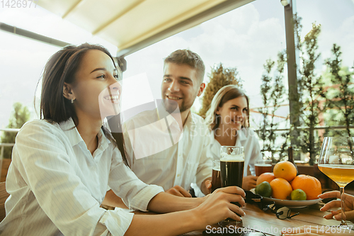 Image of Young group of friends drinking beer and celebrating together