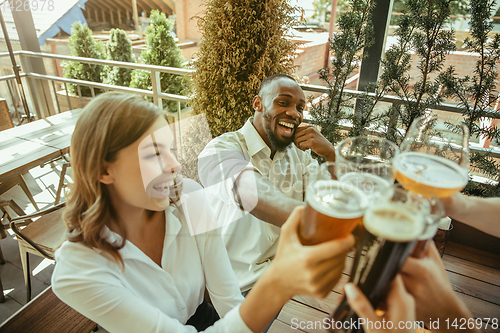 Image of Young group of friends drinking beer and celebrating together