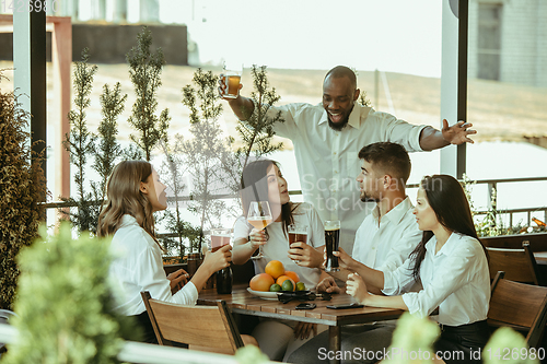 Image of Young group of friends drinking beer and celebrating together